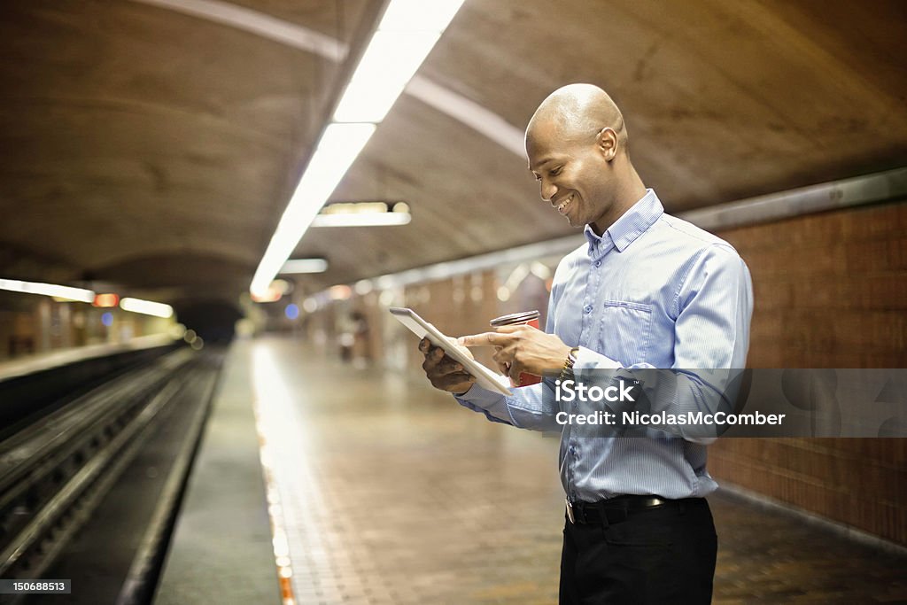 Homem africano usando tablet digital enquanto espera para o metrô - Foto de stock de Mesa digital royalty-free