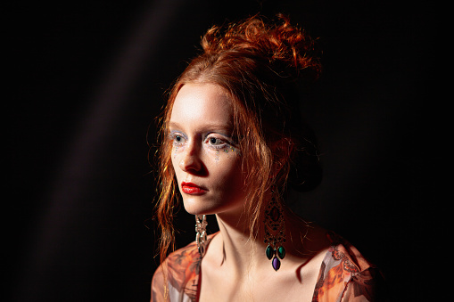 Fine art portrait of a young beautiful red-haired woman with artistic make-up