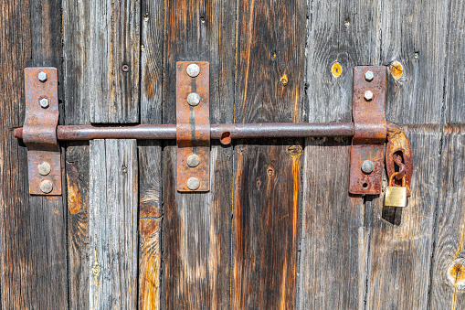 Old wooden door with iron lock and padlock, closeup of photo