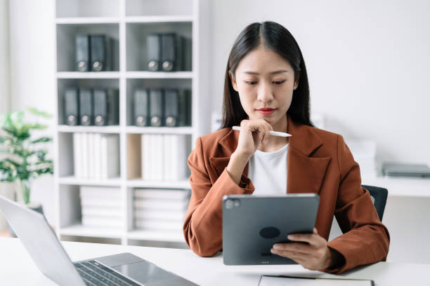 istock Business women hand working with tablet and laptop computer with documents on office desk in modern office. 1506928124