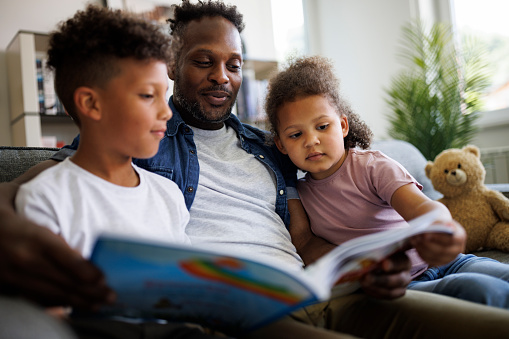 Father reading book to son and daughter. Children education and development concept