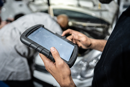 Mechanic's hands using the digital tablet at an auto repair shop