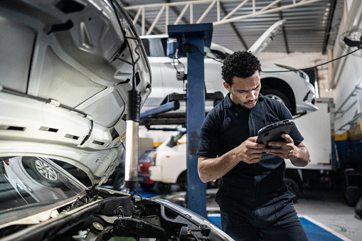 Mechanic using the digital tablet at an auto repair shop