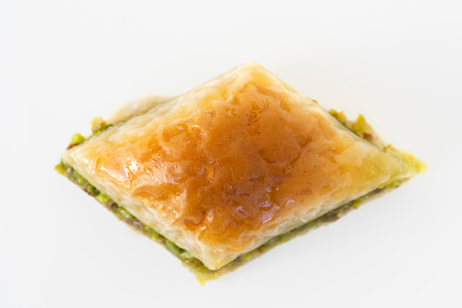 Piece of delicious baklava with pistachios isolated on white.