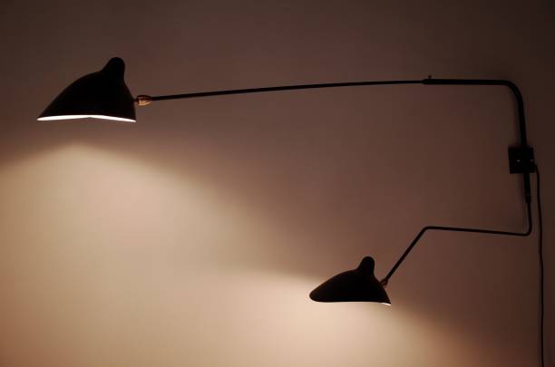 istock Modern black wall lamp on a white wall providing a soft yellow light in the room 1506969098