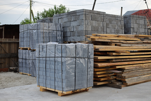 Paving stone pack in cellophane on wooden pallets for house building. Construction site.