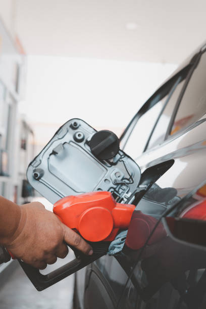 transportation and ownership concept. man pumping gasoline fuel in car at gas station - gas station fuel pump station gasoline imagens e fotografias de stock