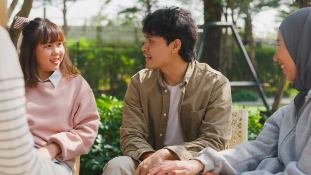 Small Asian group of people sit in a close circle and talk to a therapist in park. Smile people sharing story happy speak diverse people sitting in circle at group therapy session with psychologist. un pequeño grupo asiático de personas se sienta en un círculo cercano y habla con un terapeuta en el parque. sonríe a las personas que comparten la historia feliz hablan diversas personas sentadas en círculo en la sesión de terapia grupal del psicól