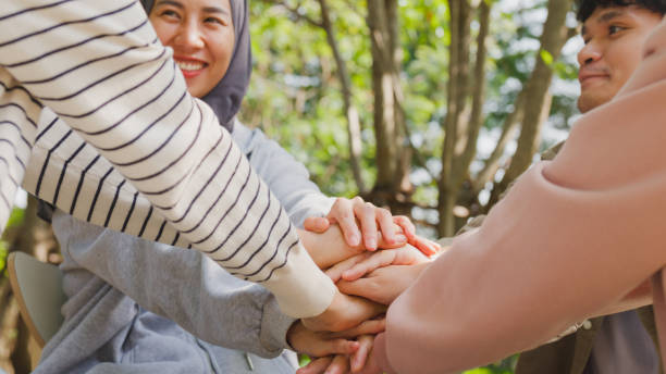 Close-up of diverse multiracial men and women group sit in circle hold hands together hope for help people in park. Support and understand at psychological therapy session, PTSD Mental health. stock photo
