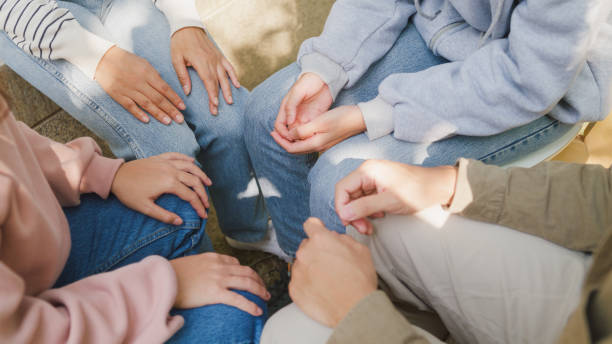 Close-up hands of diverse multiracial male and female group sit circle explain tell story sharing together in park. Support and understand at psychological therapy session, PTSD Mental health. stock photo