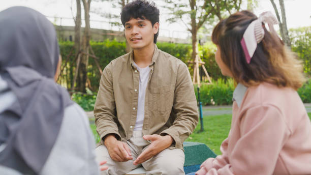 Small Asian group of people sit in a close circle and talk to a therapist in park. Smile people sharing story happy speak diverse people sitting in circle at group therapy session with psychologist. un pequeño grupo asiático de personas se sienta en un círculo cercano y habla con un terapeuta en el parque. sonríe a las personas que comparten la historia feliz hablan diversas personas sentadas en círculo en la sesión de terapia grupal del psicól