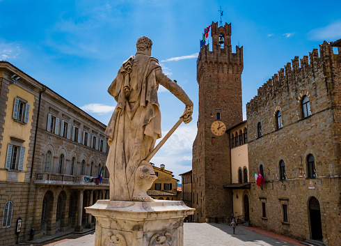 Arezzo, impressive view of Piazza Duomo and its historical buildings with Ferdinando de Medici statue in foreground, Tuscany, Italy