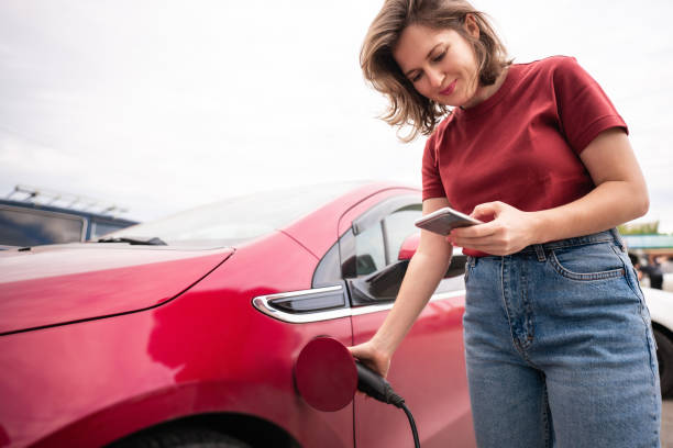 istock Woman with smartphone charging electric car 1507046635