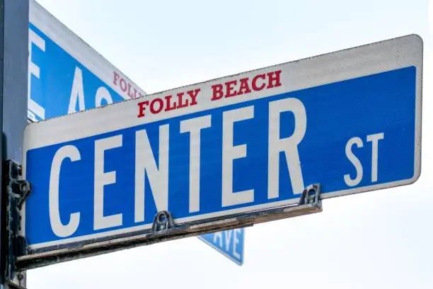 A blue and white street sign with Center Street and Folsky Beach written on it, standing in front of a blue sky