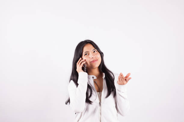 Photograph of young woman talking on the phone on a white studio background. Concept of people.