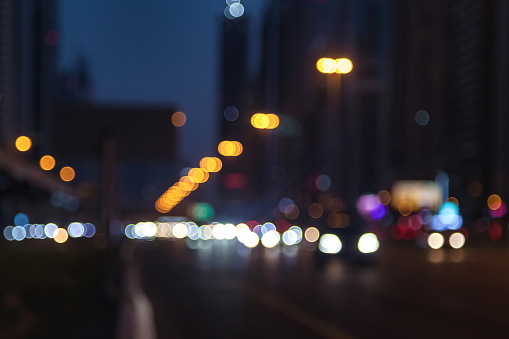 Urban view on night Dubai city highway with cars and street lamps blurred light. Abstract stylish backgrounds: defocused lights, style color tone, design concept. Copy text space, wallpaper, poster