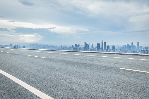 Empty asphalt road and city buildings skyline. Urban road transport scene