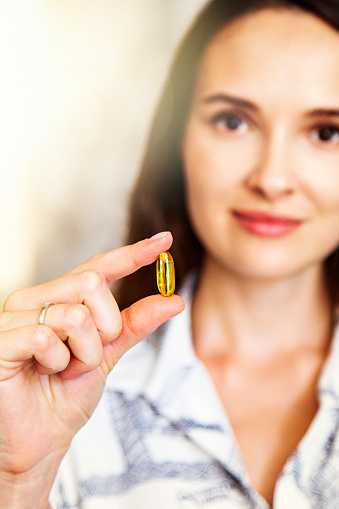 Close-up Omega-3 in a hands of beautiful young woman. Healthy lifestyle concept