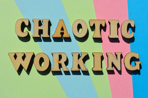 Chaotic Working, words in wooden alphabet letters isolated on background as banner headline