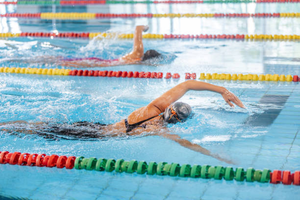 Female swimmer using freestyle technique in pool lane Athletic female swimmer using freestyle technique in pool lane, competition preparation training. Swimming tournament concept. women exercising swimming pool young women stock pictures, royalty-free photos & images