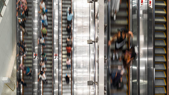 Motion blur of crowd Asian people transport on escalator at subway underground station in Hong Kong. Public transportation, Asia city life, or commuter urban lifestyle concept. Top high angle view