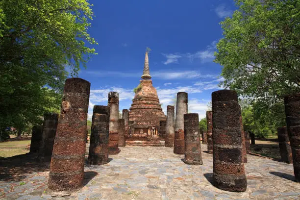 Sukhothai landmark, Wat Chang Lom pagoda attached by elephant statues with front view of old pillars and blue sky, Thailand. Famous travel destination and world heritage historical landmark in Siam.