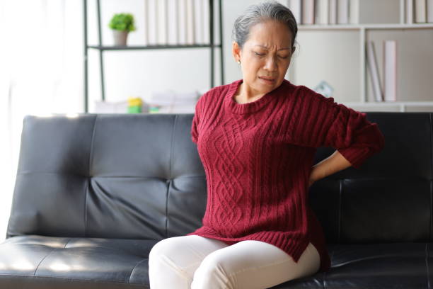 Elderly woman at home suffering from osteoarthritis has back pain.
