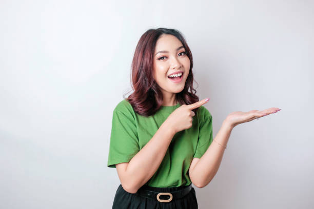 istock Smiling beautiful Asian woman pointing finger sideward to empty space isolated white background 1507303726