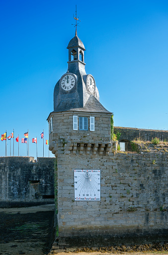 a mechanic clock and a sun dial on a tower in the harbour of Concarneau in Brittany, France