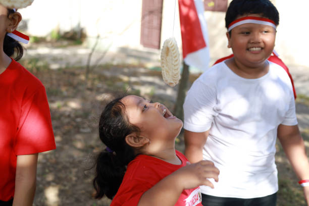 niños indonesios celebran el día de la independencia de indonesia con un concurso al aire libre - eating child cracker asia fotografías e imágenes de stock