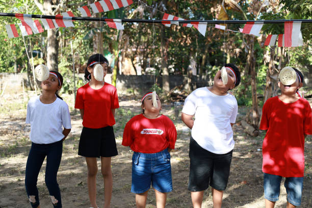 indonesian kids celebrate indonesia independence day with outdoor contest - eating child cracker asia imagens e fotografias de stock
