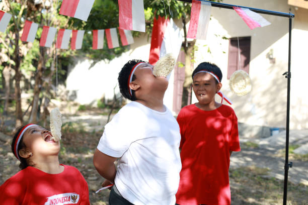 niños indonesios celebran el día de la independencia de indonesia con un concurso al aire libre - eating child cracker asia fotografías e imágenes de stock