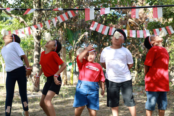 niños indonesios celebran el día de la independencia de indonesia con un concurso al aire libre - eating child cracker asia fotografías e imágenes de stock