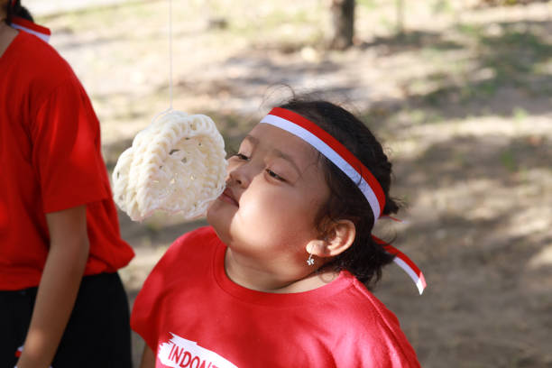 niños indonesios celebran el día de la independencia de indonesia con un concurso al aire libre - eating child cracker asia fotografías e imágenes de stock
