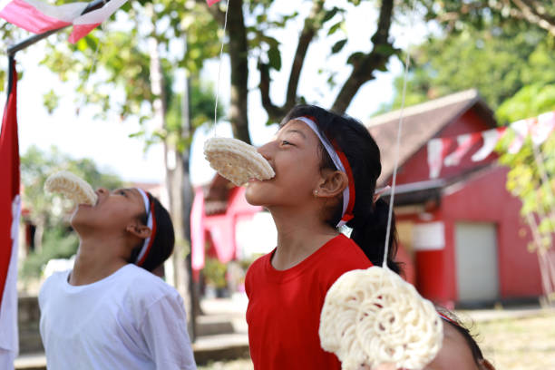 niños indonesios celebran el día de la independencia de indonesia con un concurso al aire libre - eating child cracker asia fotografías e imágenes de stock