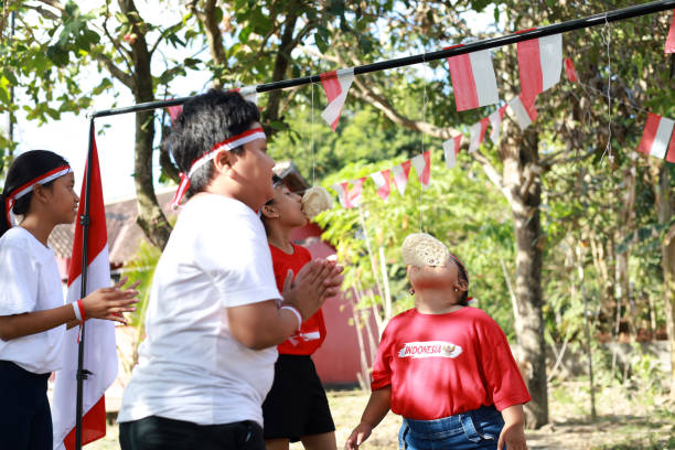 niños indonesios celebran el día de la independencia de indonesia con un concurso al aire libre - eating child cracker asia fotografías e imágenes de stock