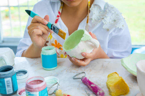Ceramist painting a clay cup in an atelier