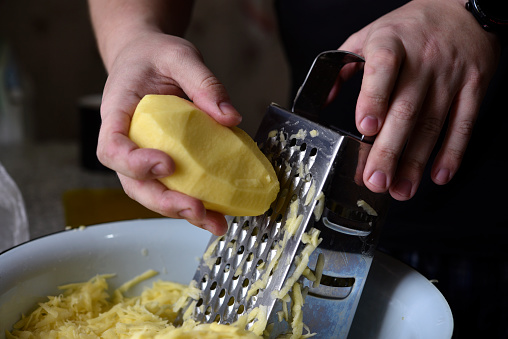 Cleaning of fresh potatoes. Cutting potatoes. Cutting potatoes on a grater. Iron grater for vegetables.