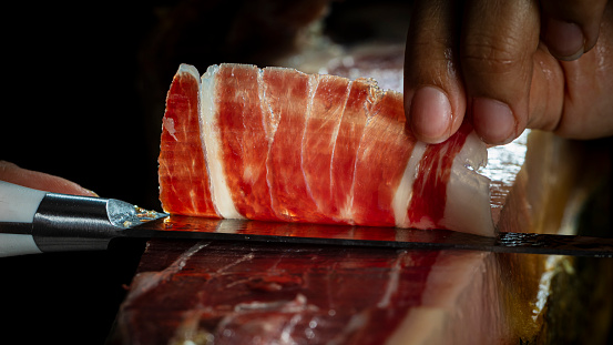 A close-up view of a perfectly sliced, hand-carved Iberian ham