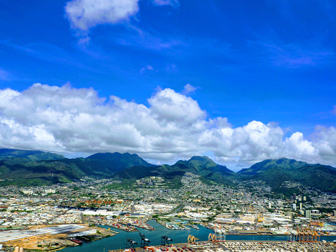 Aerial of Honolulu Harbor and Shipping docks with city and mountains in the distance