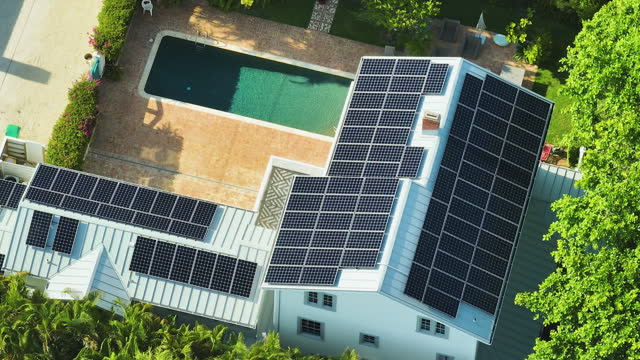 Expensive american residential house with rooftop covered with solar photovoltaic panels for producing of clean ecological electrical energy in suburban rural area. Concept of autonomous home