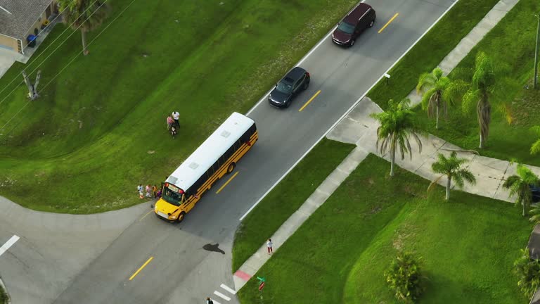 Top view of standard american yellow school bus picking up kids at rural town street stop for their lessongs in early morning. Public transport in the USA