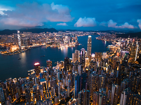 Cityscape night view of Hong Kong island, drone aerial high angle view. Skyscraper buildings in financial district, ship transportation on Victoria harbour. Asia tourism travel, tourist landmark