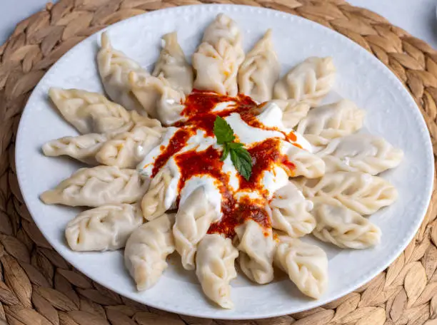 Photo of Traditional manti food on plate, top view. The concept of oriental cuisine. Uzbek food manty dumplings. (Turkish name; hinkel mantisi + cecen mantisi)