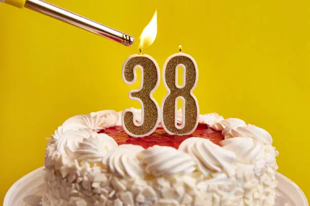A candle in the form of the number 38, stuck in a festive cake, is lit. Celebrating a birthday or a landmark event. The climax of the celebration.