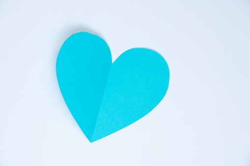 one paper blue heart cut out on colored background closeup