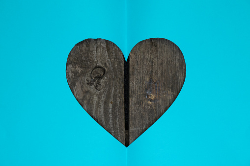 one paper blue heart cut out lies on a wooden background close up