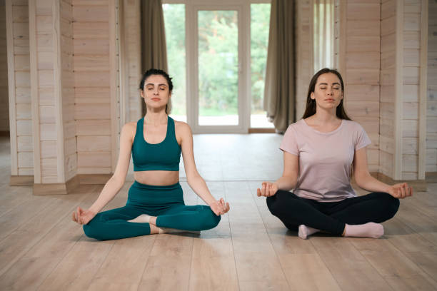 istock Women sitting in lotus position on floor 1507671816