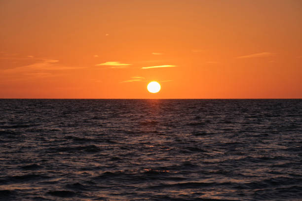 istock Ocean sunset. Big white sun on dramatic bright sky background, soft evening cloud over sea dark water 1507696134