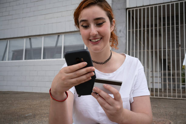 istock Happy lady paying online via mobile phone against building 1507765615